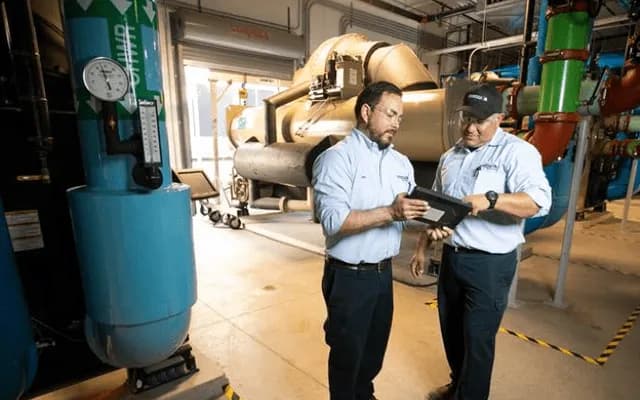 Comfort Systems USA employees reviewing a tablet in a mechanical room, a Workmates customer