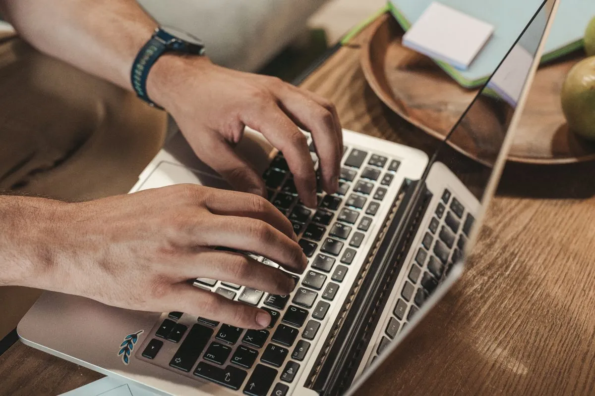 Close-up of a professional typing a job post on a laptop